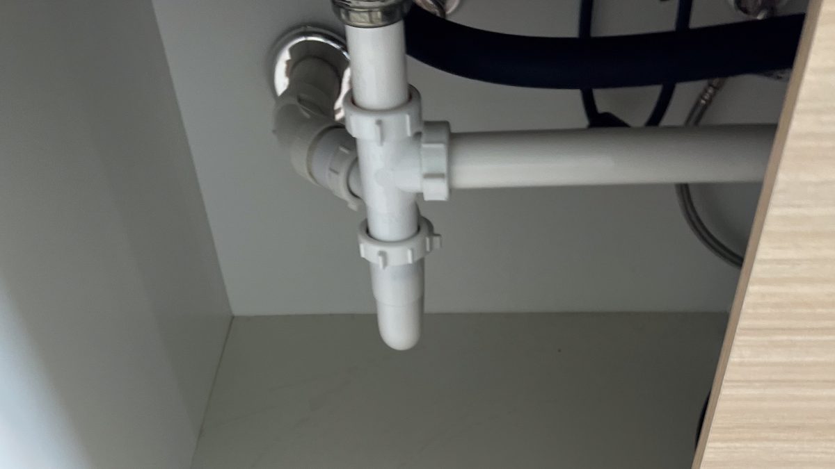 PVC drain and supply pipes under a kitchen sink cabinet, the exposed pipes you protect by opening the cabinet doors to prevent frozen pipes