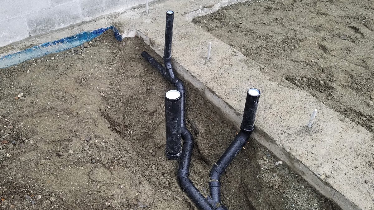 Plastic supply and drain pipes under a home's foundation before the concrete slab is poured, the kind of plumbing where a leaking pipe under a slab can later occur