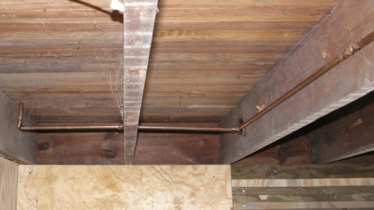 Copper water pipes along a house basement ceiling, the type of plumbing where a leaking water pipe in house often begins