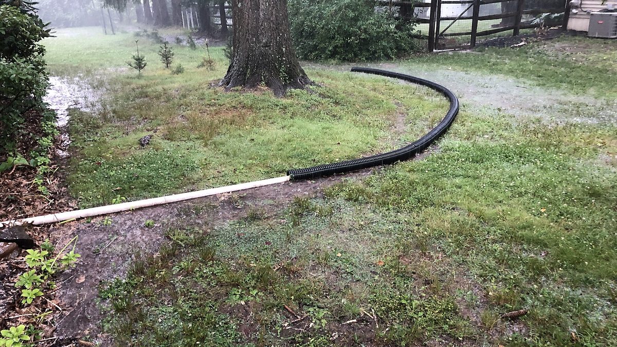 Standing water flooding a yard outside a house, similar to the aftermath of a burst outdoor water pipe