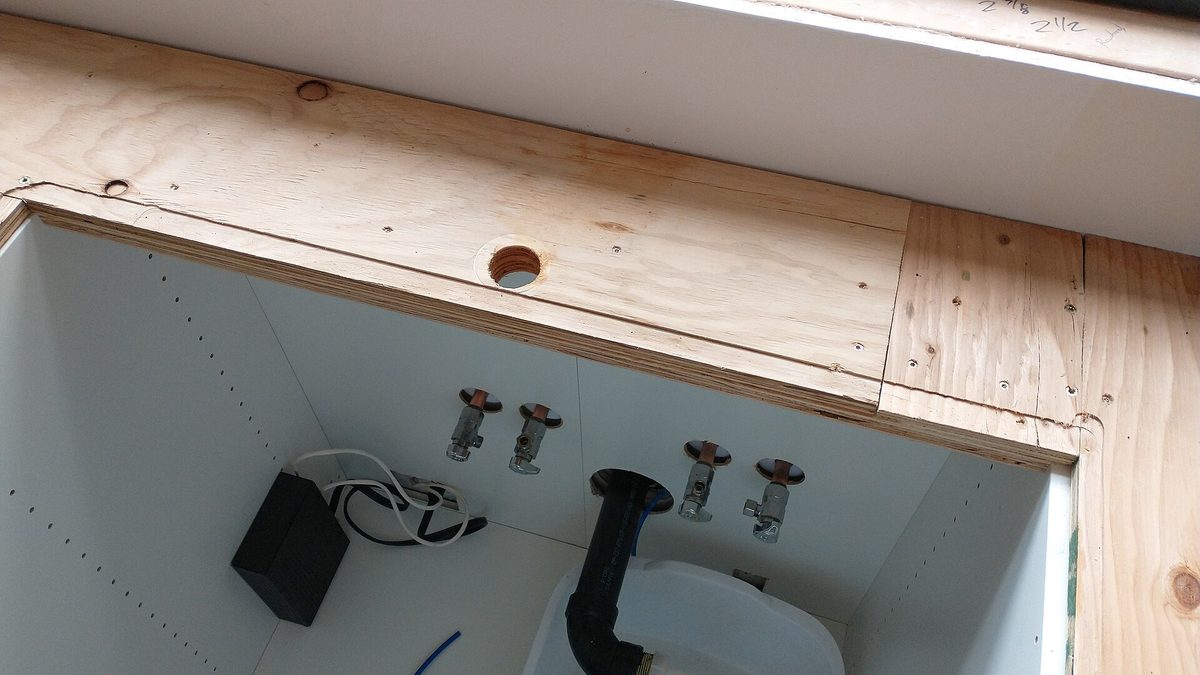 Angle stop shutoff valves and a P-trap drain pipe under a kitchen sink cabinet during installation