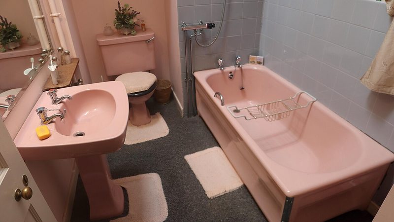 Pink bathroom with toilet, sink and tub, where a toilet overflowing can soak the floor