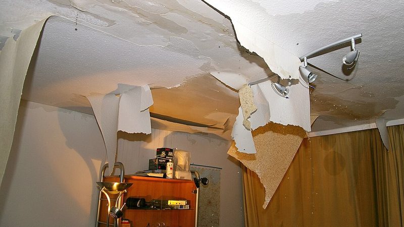 Water-damaged ceiling drywall sagging and dripping after a leak soaked through from the room above