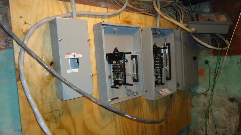 Open electrical breaker panels and wiring mounted in a home basement, the kind of equipment water damage can make dangerous