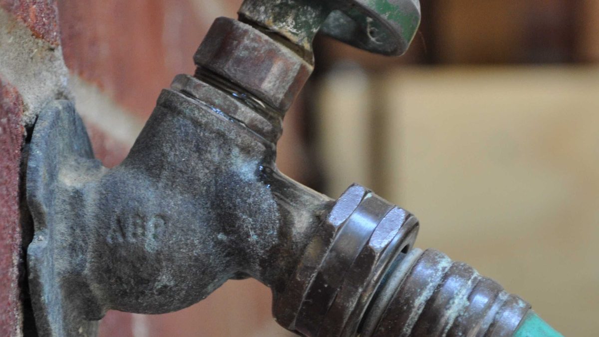 Outdoor hose bib on a brick house wall, used to check that the main water shutoff valve worked